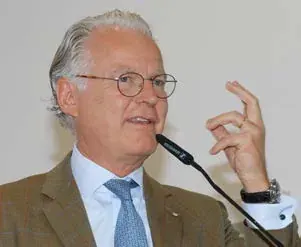 Ein Redner mit Brille und Krawatte spricht gestikulierend in ein Mikrofon